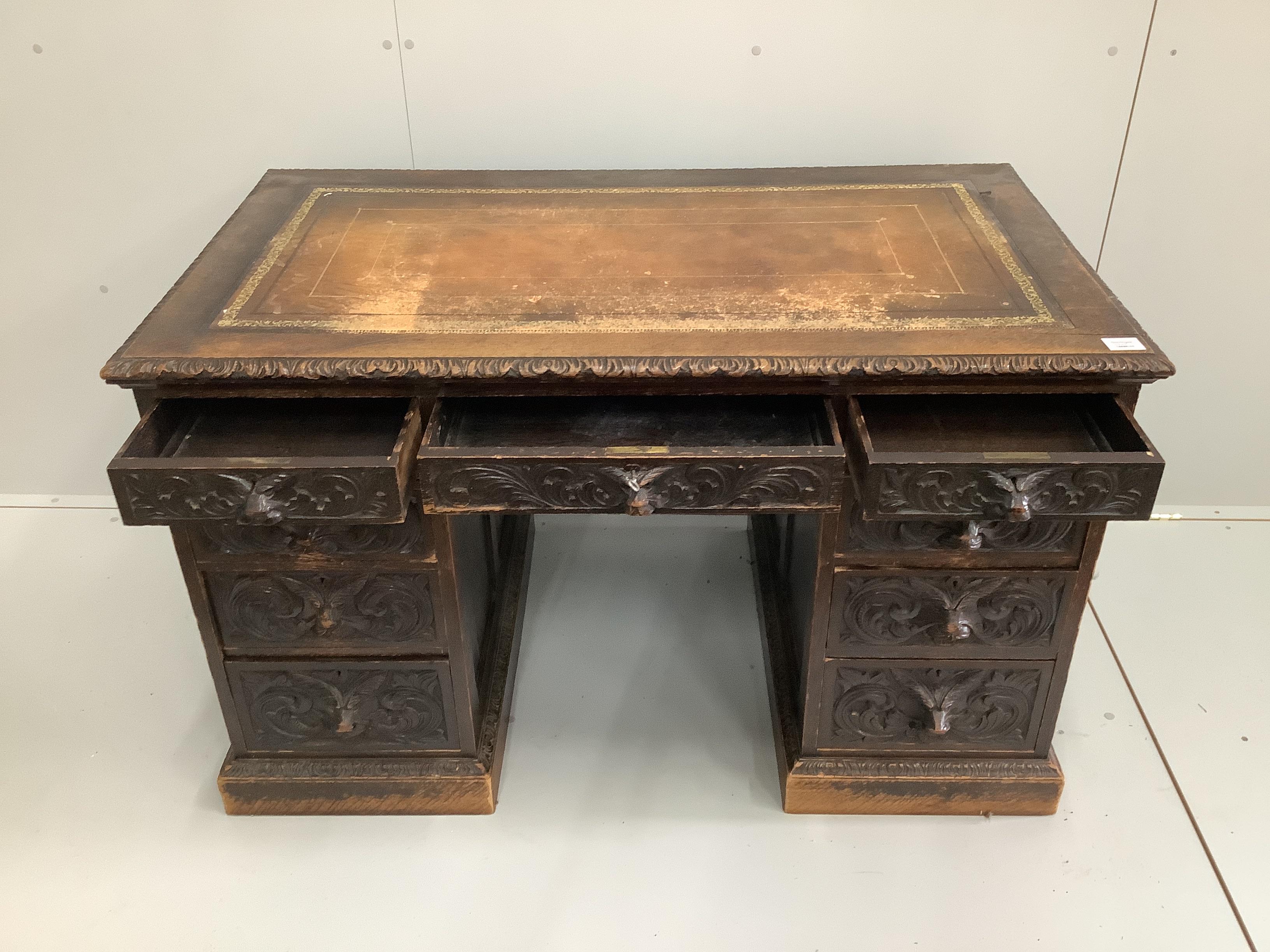 A late Victorian carved oak pedestal desk with lion mask cup handles, width 122cm, depth 70cm, height 75cm